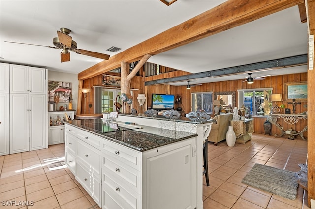 kitchen featuring ceiling fan, wood walls, and white cabinetry