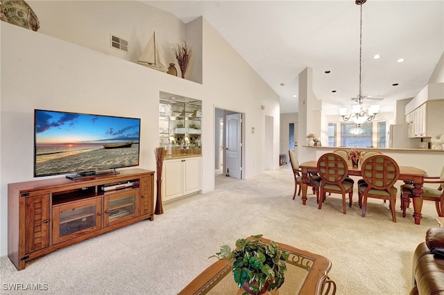 carpeted living room featuring a chandelier and high vaulted ceiling