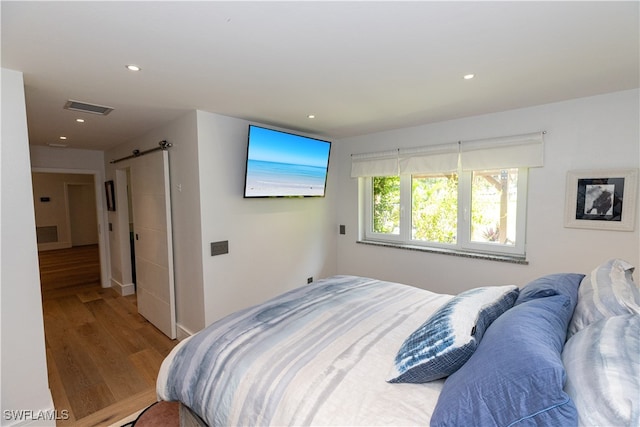 bedroom featuring a barn door and hardwood / wood-style floors