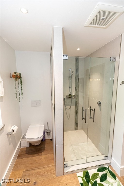 bathroom featuring walk in shower, hardwood / wood-style floors, and toilet