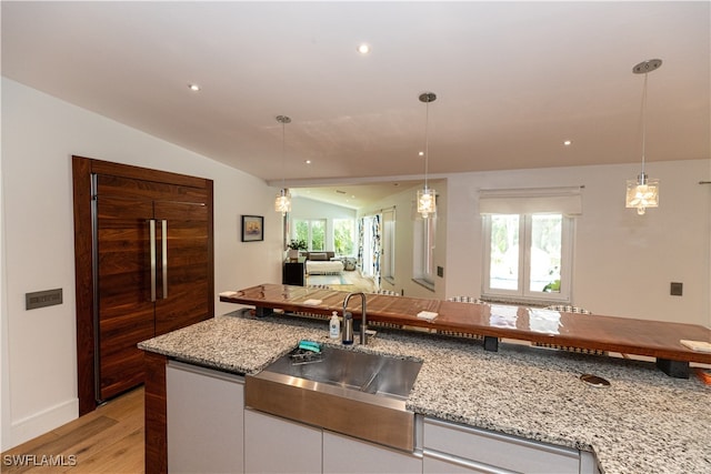 kitchen featuring lofted ceiling, light hardwood / wood-style floors, white cabinetry, and a wealth of natural light