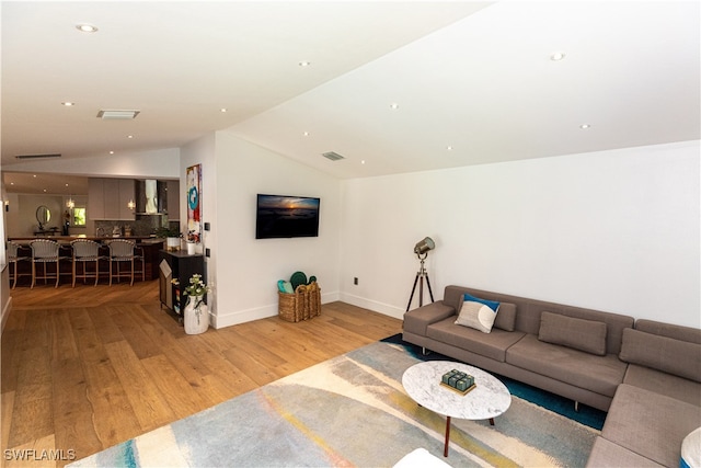 living room with light hardwood / wood-style flooring and vaulted ceiling