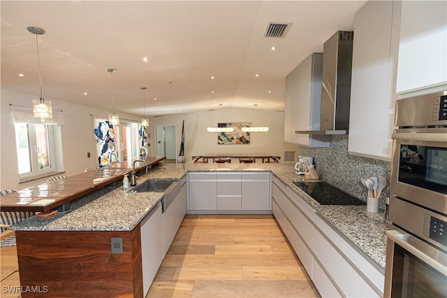 kitchen with white cabinetry, kitchen peninsula, light hardwood / wood-style floors, and sink