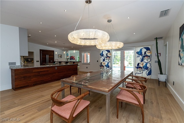 dining space featuring sink, french doors, an inviting chandelier, light wood-type flooring, and vaulted ceiling