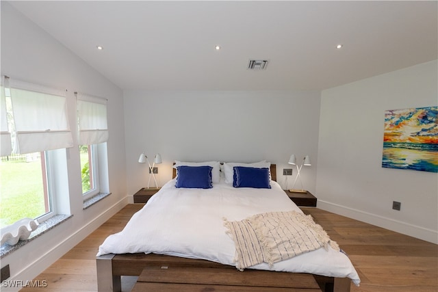 bedroom with light wood-type flooring and vaulted ceiling