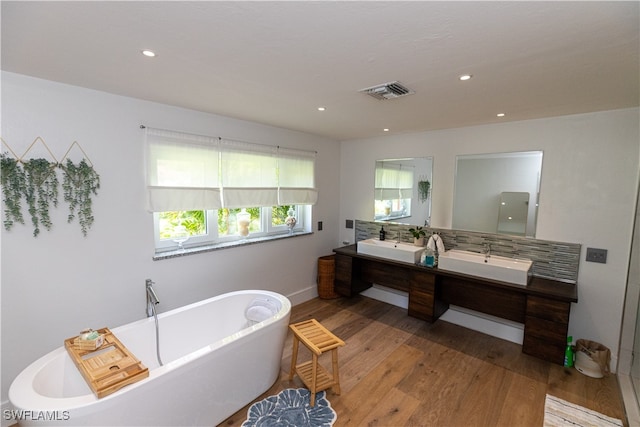 bathroom with decorative backsplash, vanity, hardwood / wood-style flooring, and a bathtub