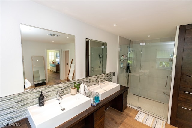 bathroom with hardwood / wood-style flooring, backsplash, vanity, and a shower with shower door