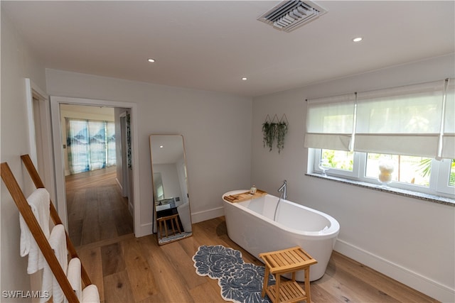 bathroom featuring wood-type flooring and a tub to relax in