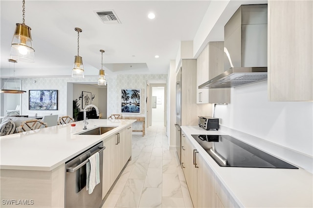 kitchen featuring hanging light fixtures, wall chimney exhaust hood, a center island with sink, stainless steel dishwasher, and sink