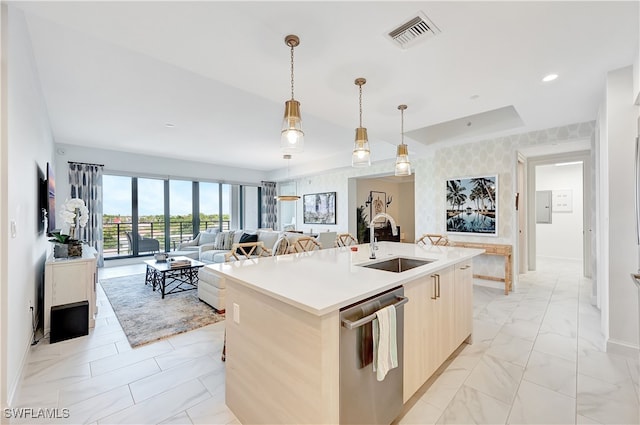 kitchen with a center island with sink, hanging light fixtures, sink, and stainless steel dishwasher