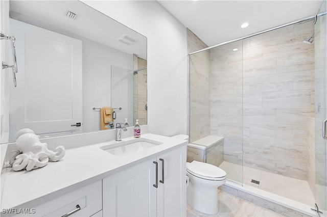 bathroom featuring a shower with door, vanity, and toilet