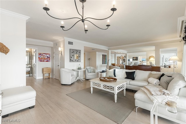 living room with crown molding, a chandelier, and light wood-type flooring