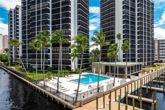 view of pool with a patio, a water view, and a dock