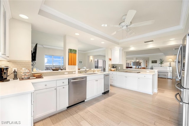 kitchen with white cabinetry, stainless steel appliances, backsplash, kitchen peninsula, and light hardwood / wood-style floors