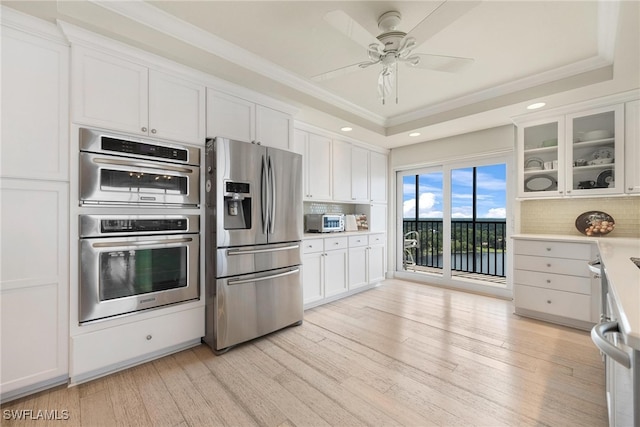 kitchen with ceiling fan, appliances with stainless steel finishes, tasteful backsplash, light hardwood / wood-style floors, and white cabinetry