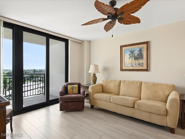 living room with light hardwood / wood-style floors, ceiling fan, a wall of windows, and a textured ceiling