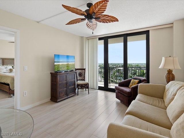 living room featuring light wood-type flooring, ceiling fan, plenty of natural light, and expansive windows