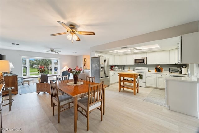 dining room with ceiling fan, light hardwood / wood-style flooring, and sink