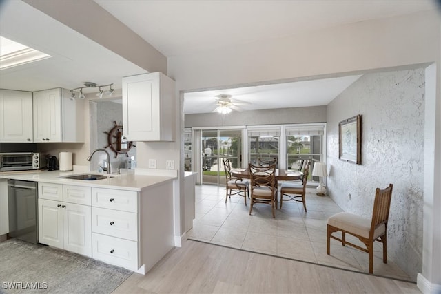 kitchen featuring sink, white cabinetry, light hardwood / wood-style flooring, ceiling fan, and stainless steel dishwasher