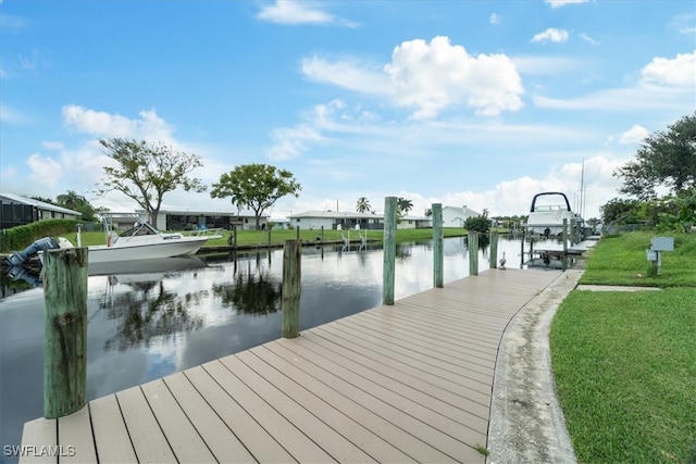 view of dock with a lawn and a water view