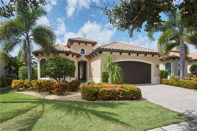 mediterranean / spanish home featuring a front lawn and a garage