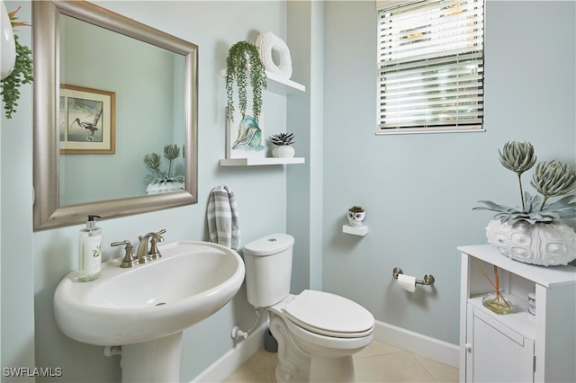 bathroom with toilet, sink, and tile patterned floors