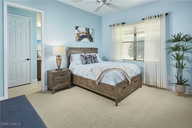 bedroom with light carpet, ensuite bathroom, and ceiling fan