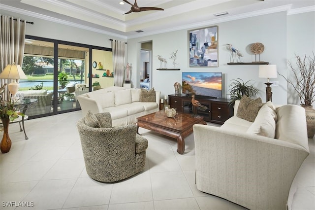 living room with ceiling fan, a raised ceiling, ornamental molding, and light tile patterned floors