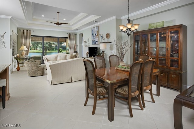 tiled dining area with ornamental molding, a tray ceiling, and ceiling fan with notable chandelier