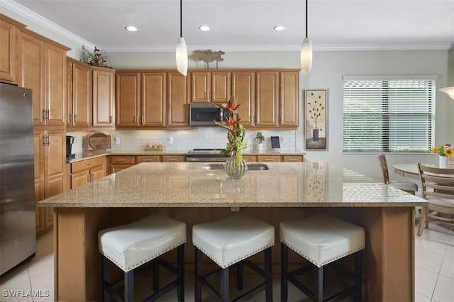 kitchen featuring stainless steel appliances, decorative light fixtures, and a center island with sink