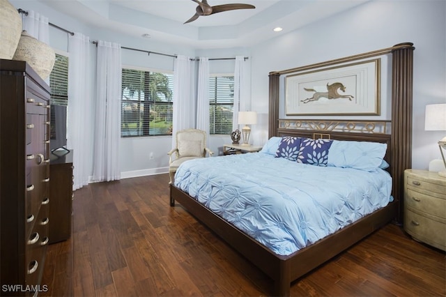 bedroom with dark wood-type flooring, ceiling fan, and a raised ceiling