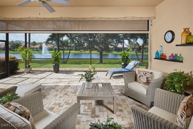 sunroom / solarium featuring a water view and ceiling fan