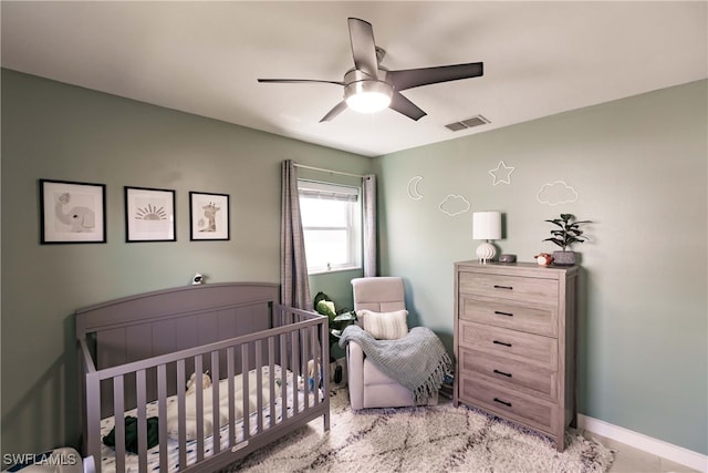 bedroom with ceiling fan and a nursery area