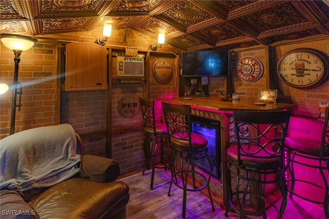 bar featuring an AC wall unit, brick wall, and hardwood / wood-style flooring