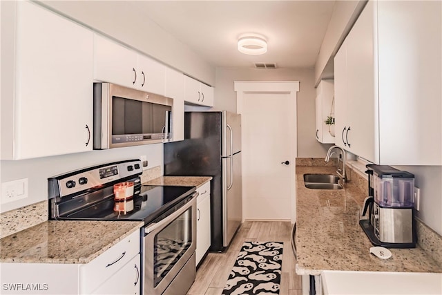 kitchen with white cabinetry, light stone countertops, light wood-type flooring, sink, and stainless steel appliances