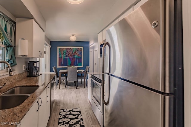 kitchen with light hardwood / wood-style floors, white cabinetry, stainless steel appliances, and light stone counters