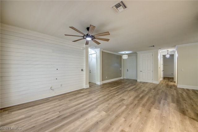 interior space with ornamental molding, light wood-type flooring, wood walls, and ceiling fan