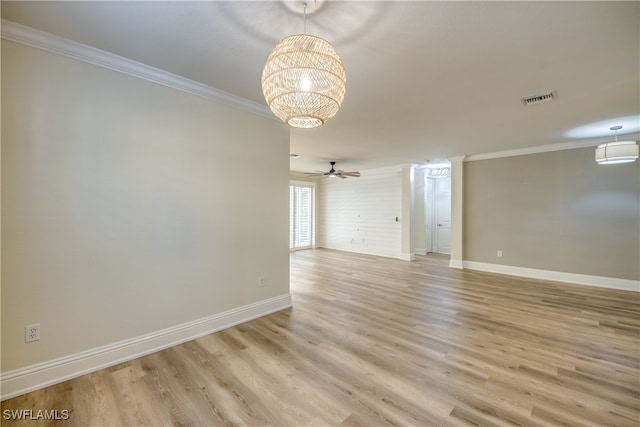 empty room with ceiling fan with notable chandelier, light wood-type flooring, and crown molding