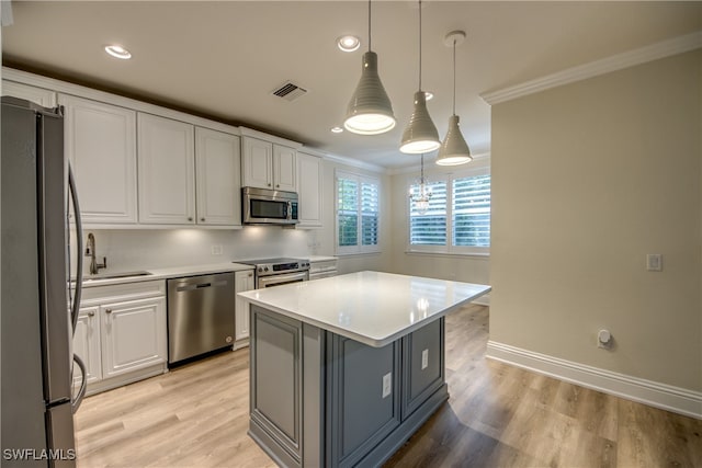 kitchen with white cabinets, a kitchen island, pendant lighting, stainless steel appliances, and sink