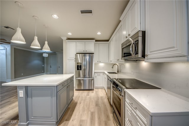 kitchen with a kitchen island, appliances with stainless steel finishes, hanging light fixtures, and white cabinetry