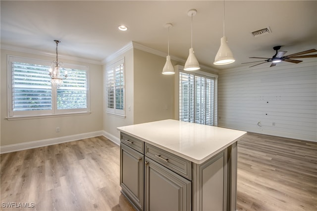 kitchen featuring ceiling fan with notable chandelier, crown molding, decorative light fixtures, a center island, and a wealth of natural light