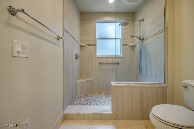 bathroom featuring a tile shower, tile patterned flooring, and toilet