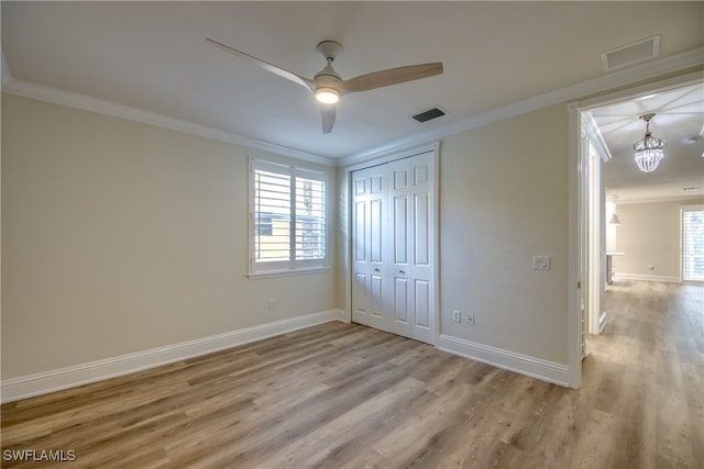 unfurnished bedroom with ceiling fan with notable chandelier, ornamental molding, light hardwood / wood-style flooring, and a closet