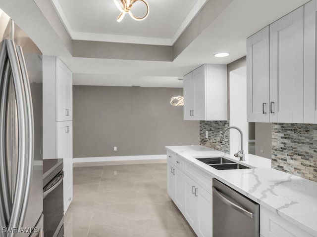 kitchen featuring appliances with stainless steel finishes, sink, white cabinets, and a tray ceiling