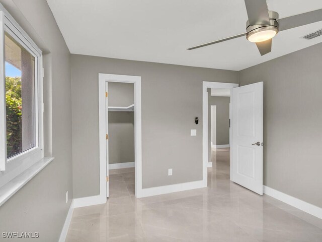 unfurnished bedroom with ceiling fan, a walk in closet, light tile patterned floors, and a closet