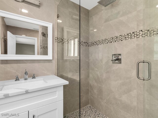 bathroom featuring backsplash, tile walls, a shower with shower door, and sink