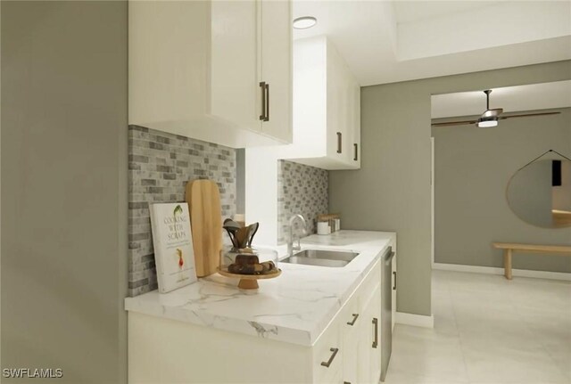 kitchen with light stone countertops, backsplash, white cabinetry, and sink