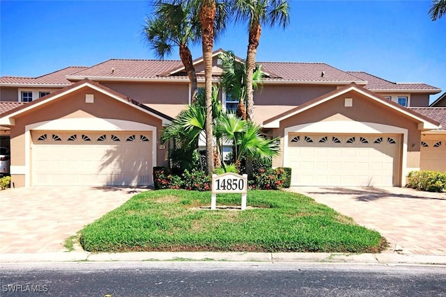 14850 Crystal Cove Ct Unit 402, Fort Myers, FL 33919 - view of front of home featuring a garage, a tile roof, stucco siding, and driveway