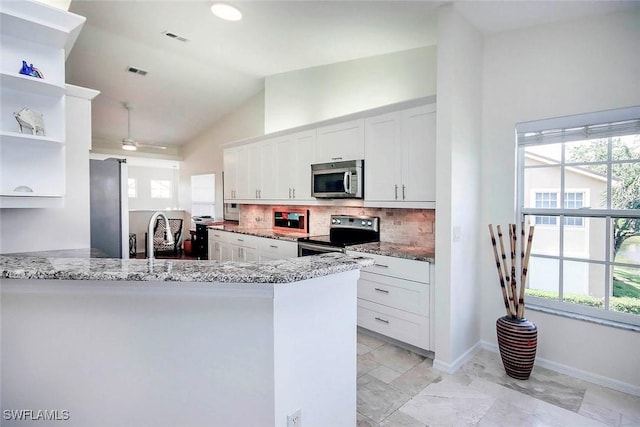 14850 Crystal Cove Ct Unit 402, Fort Myers, FL 33919 - kitchen with open shelves, lofted ceiling, white cabinets, backsplash, and appliances with stainless steel finishes