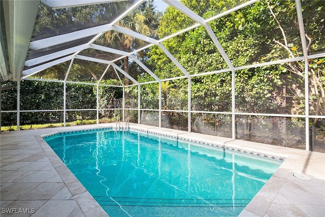 view of pool featuring glass enclosure and a patio area